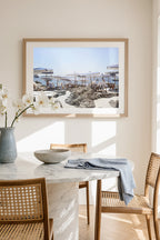Fine art photography print of Capri beach club with striped umbrellas, framed wall art displayed in a light-filled dining nook.