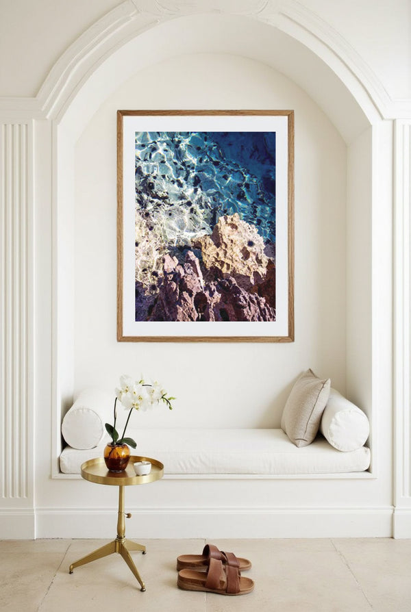 Framed art print of turquoise waters and rocky shoreline in Croatia, styled in a Mediterranean reading nook with arched alcove.