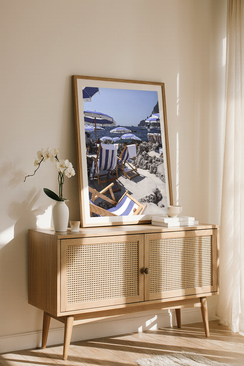 Art print of La Fontelina Beach Club in Capri, framed wall art leaning on a console with sunlight streaming in.