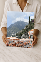 Coastal wall art print of Positano, Italy with vibrant beach club views. A Mediterranean travel photography print ideal for stylish home décor spaces.